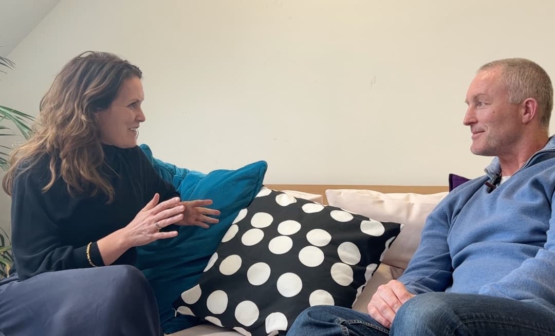 Sinead Gillett and Bob Nixon sitting across from each other on a sofa, mid-conversation for the launch interview